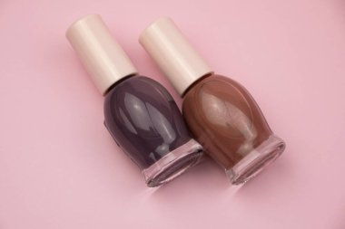 Pembe arka planda küçük cam şişeler, profesyonel manikür konsepti.