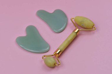 Gua Sha yüz araçları, arka planda fotokopi alanı olan yeşil taş masaj silindiri, metin için yeri olan spa arka planı, cilt bakımı