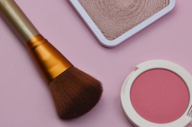 Pembe arka planda makyaj fırçası ve pudra seti.