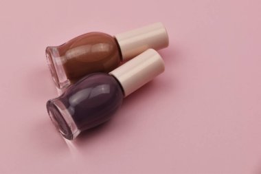 Pembe arka planda küçük cam şişeler, profesyonel manikür konsepti.