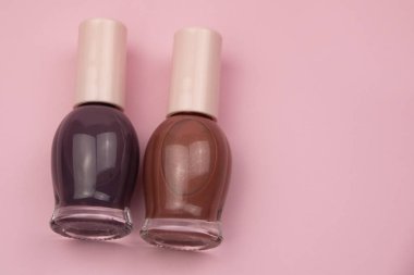 Pembe arka planda küçük cam şişeler, profesyonel manikür konsepti.