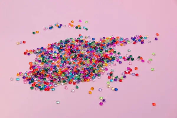 Colorful beads scattered on a pink background. Place for text.
