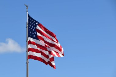 Rüzgarda dalgalanan Amerikan bayrağı ve arkasında mavi bir gökyüzü