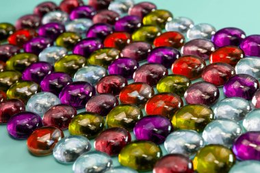 Mavi arka planda farklı şekil ve boyutlarda çok renkli cam boncuklar.