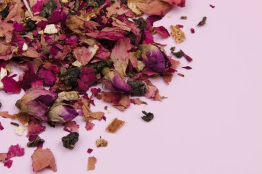 Pembe arka planda kurumuş gül yaprakları, yakın planda mor gül çiçekleri, romantik çiçek deseni.