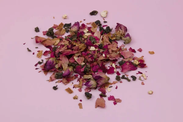 Dried rose petals on a pink background, purple rose flowers close-up, romantic floral texture