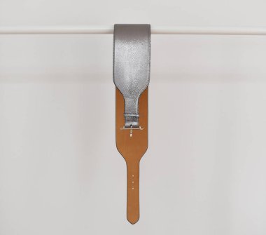 Beyaz bir arkaplanda askıdaki deri kemer.