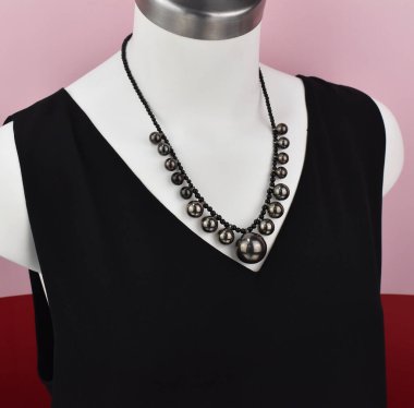 Beyaz bir mankenin üzerindeki ifade kolyesi, devasa el yapımı takılar.