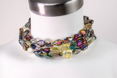 Beyaz bir mankenin üzerindeki ifade kolyesi, devasa el yapımı takılar.