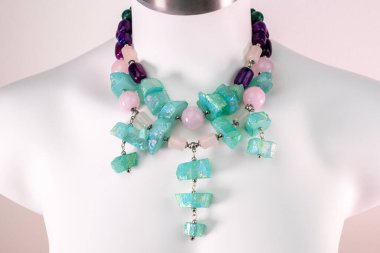 Beyaz bir mankenin üzerindeki ifade kolyesi, devasa el yapımı takılar.