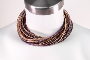 Beyaz bir mankenin üzerindeki ifade kolyesi, devasa el yapımı takılar.