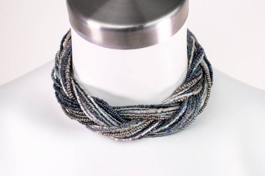 Beyaz bir mankenin üzerindeki ifade kolyesi, devasa el yapımı takılar.