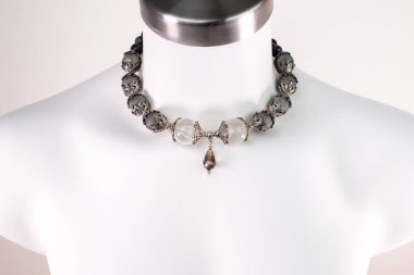 Beyaz bir mankenin üzerindeki ifade kolyesi, devasa el yapımı takılar.