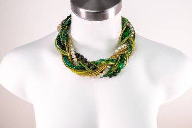 Beyaz bir mankenin üzerindeki ifade kolyesi, devasa el yapımı takılar.