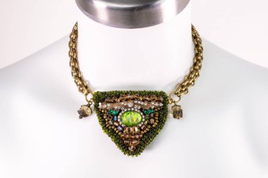 Beyaz bir mankenin üzerindeki ifade kolyesi, devasa el yapımı takılar.