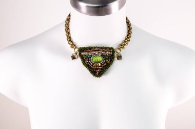 Stüdyoda beyaz arka planda bir mankenin üzerindeki kolye.