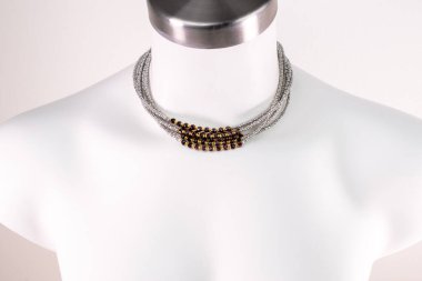 Beyaz bir mankenin üzerindeki ifade kolyesi, devasa el yapımı takılar.