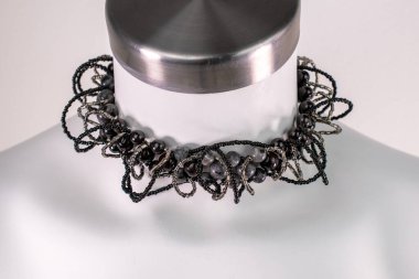 Beyaz bir mankenin üzerindeki ifade kolyesi, devasa el yapımı takılar.