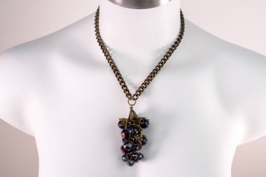 Beyaz bir mankenin üzerindeki ifade kolyesi, devasa el yapımı takılar.