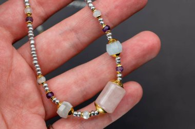 Kadının eli, üzerinde değerli taşlar olan bir bileziği tutuyor.