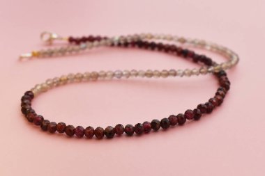 Pembe arka planda doğal taş boncuklardan yapılmış kolye..