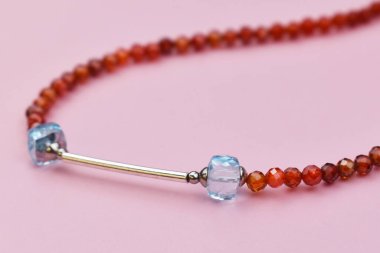 Pembe arka planda kehribar boncuklardan yapılmış kolye. Yakın plan.