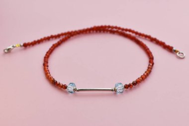 Pembe arka planda kolye. Kırmızı boncuklardan yapılmış bilezik.