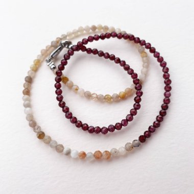 Beyaz arkaplanda farklı renkte boncuk bileziği.