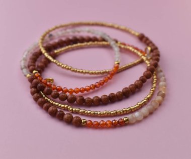 Pembe arkaplanda farklı renkte boncukların kolyesi.