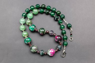Gri arkaplanda yeşil ve mavi boncuklardan yapılmış kolye