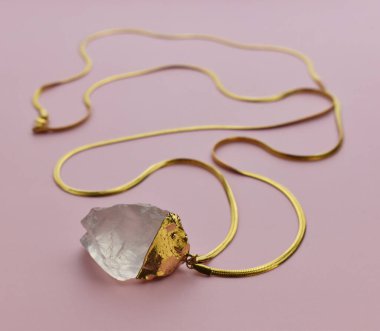 Pastel pembe arka planda altın zincirli kehribar kolye