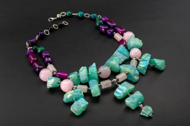 Siyah arka planda doğal taşlardan yapılmış bir kolye.