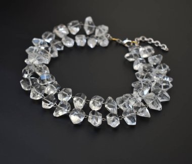 Siyah arka planda şeffaf taşlardan yapılmış kolye.