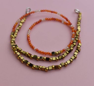 Pembe arka planda kehribar boncuklardan yapılmış bilezik. Yakın plan.