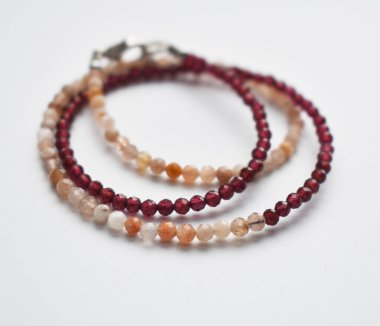 Beyaz bir zemin üzerinde doğal taşlar ve boncuklardan yapılmış bilezik.