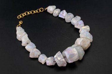 Siyah arka planda doğal kuvars kristallerinden yapılmış bir kolye.