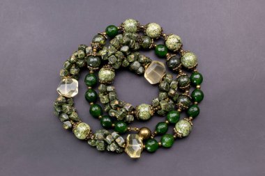 Gri arkaplanda yeşil ve sarı taşlardan yapılmış bilezik.
