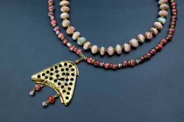 Siyah arkaplanda değerli taşlar ve boncuklardan yapılmış bir kolye.