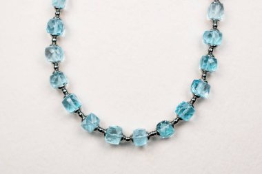 Beyaz arkaplanda turkuaz taşlı kolye.