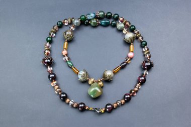 Gri arkaplanda doğal taşlardan yapılmış kolye.