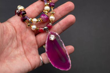 Karanlık bir arka planda ametist kuvars yarı değerli boncuklarla el.