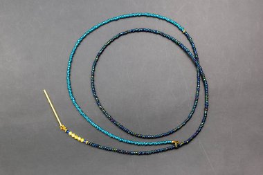 Gri arkaplanda mavi boncuklardan yapılmış kolye. Üst görünüm