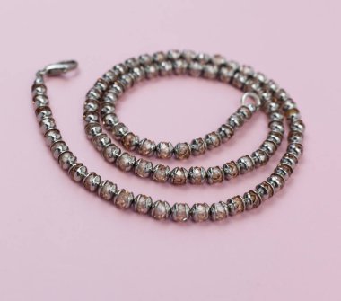 Mücevherler. Pembe arka planda gümüş boncuklardan yapılmış bilezik.