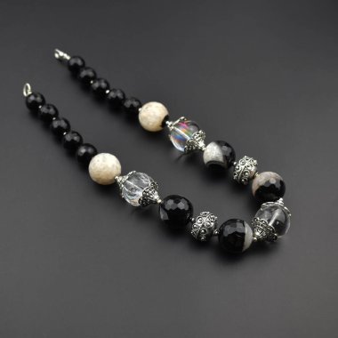 Siyah arkaplanda siyah beyaz taşlardan yapılmış bilezik.