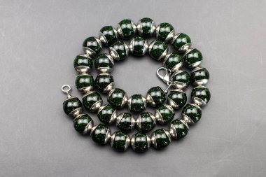 Gri arkaplanda yeşil cam boncuklardan yapılmış bilezik..