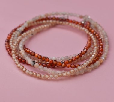 Pembe arka plandaki boncuklardan yapılmış kolye.