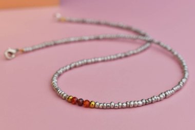Pembe arkaplandaki boncuklardan yapılmış kolye. Seçici odak.