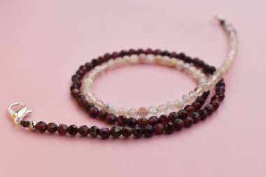 Pembe arka planda doğal taş boncuklardan yapılmış bilezik..