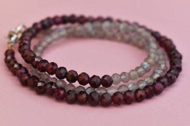 Pembe arka planda doğal taşlardan yapılmış bilezik.