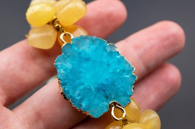 Elinde turkuaz kolye, koyu bir arkaplanda. Yakın plan.